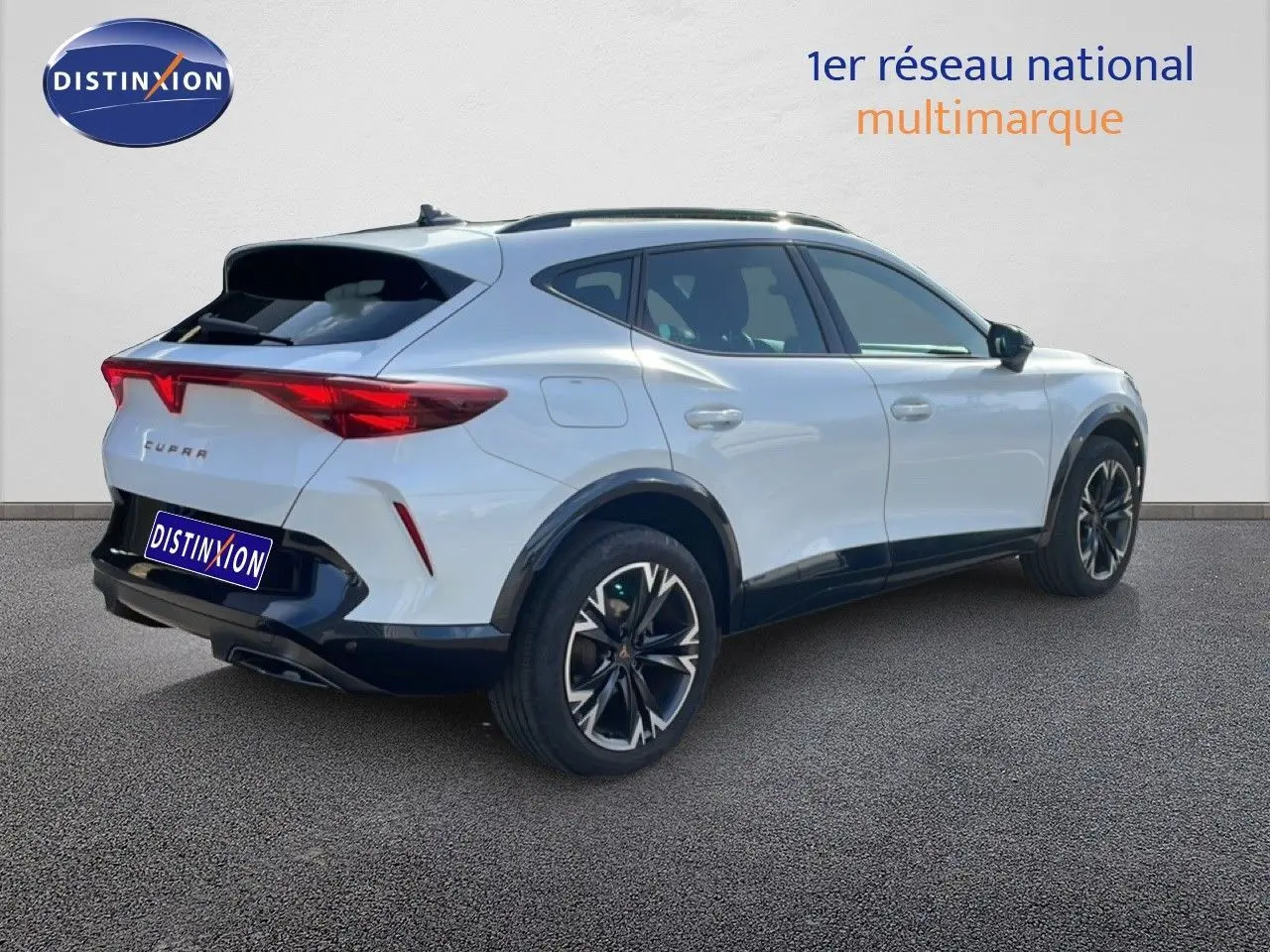 Vue 3/4 arrière droite d'un CUPRA Formentor blanc neige métal avec jantes noires et feux arrière LED distinctifs.