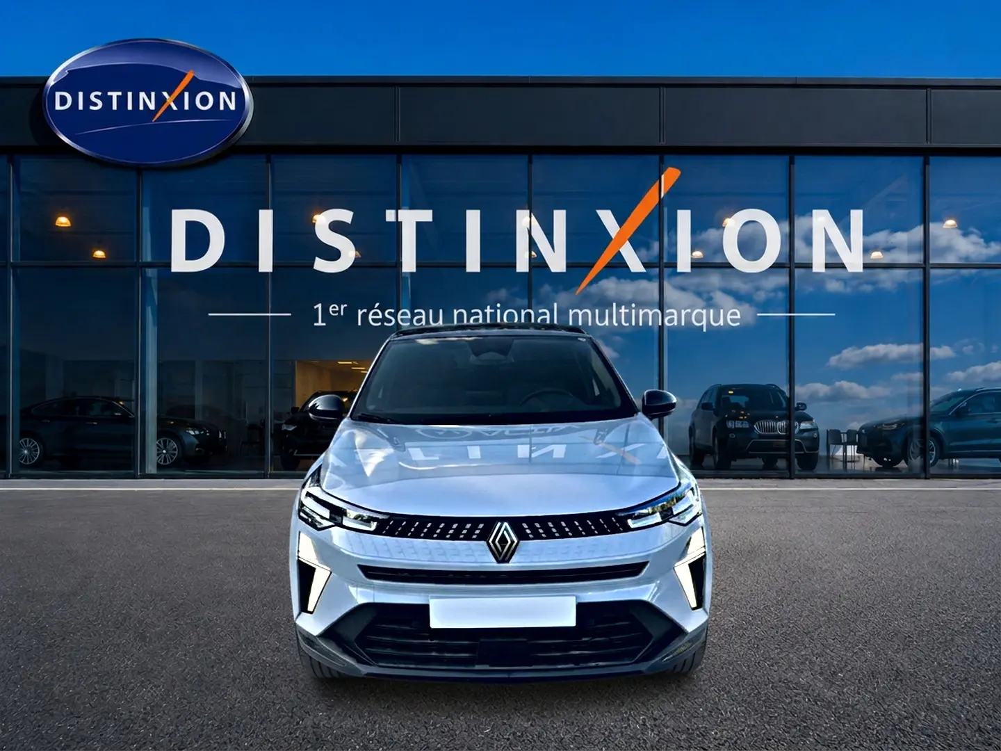 Vue avant du Renault Captur gris rafale 2026, avec calandre noire et logo Renault bien visible, devant une vitrine Distinxion.