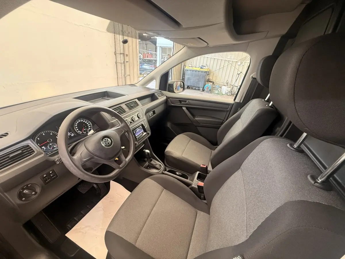 Vue intérieure avant droite du Volkswagen Caddy 2019, sièges gris et tableau de bord avec écran tactile.