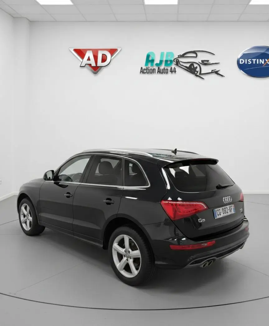 Audi Q5 noir vue 3/4 arrière droit, avec jantes alliage cinq branches et double sortie d’échappement.
