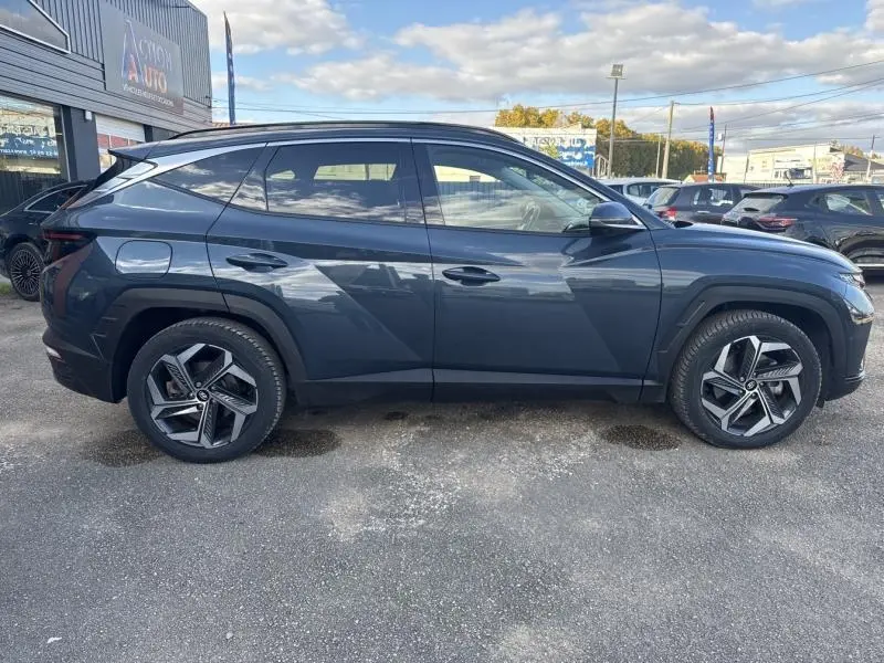 Profil côté gauche d'un Hyundai Tucson 2021 Teal Blue Métal avec jantes alliage et lignes anguleuses marquées.