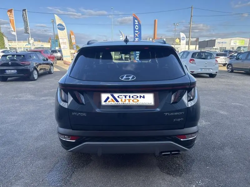 Vue arrière d'un Hyundai Tucson Teal Blue Métal avec feux LED et double sortie d'échappement visible sur parking.