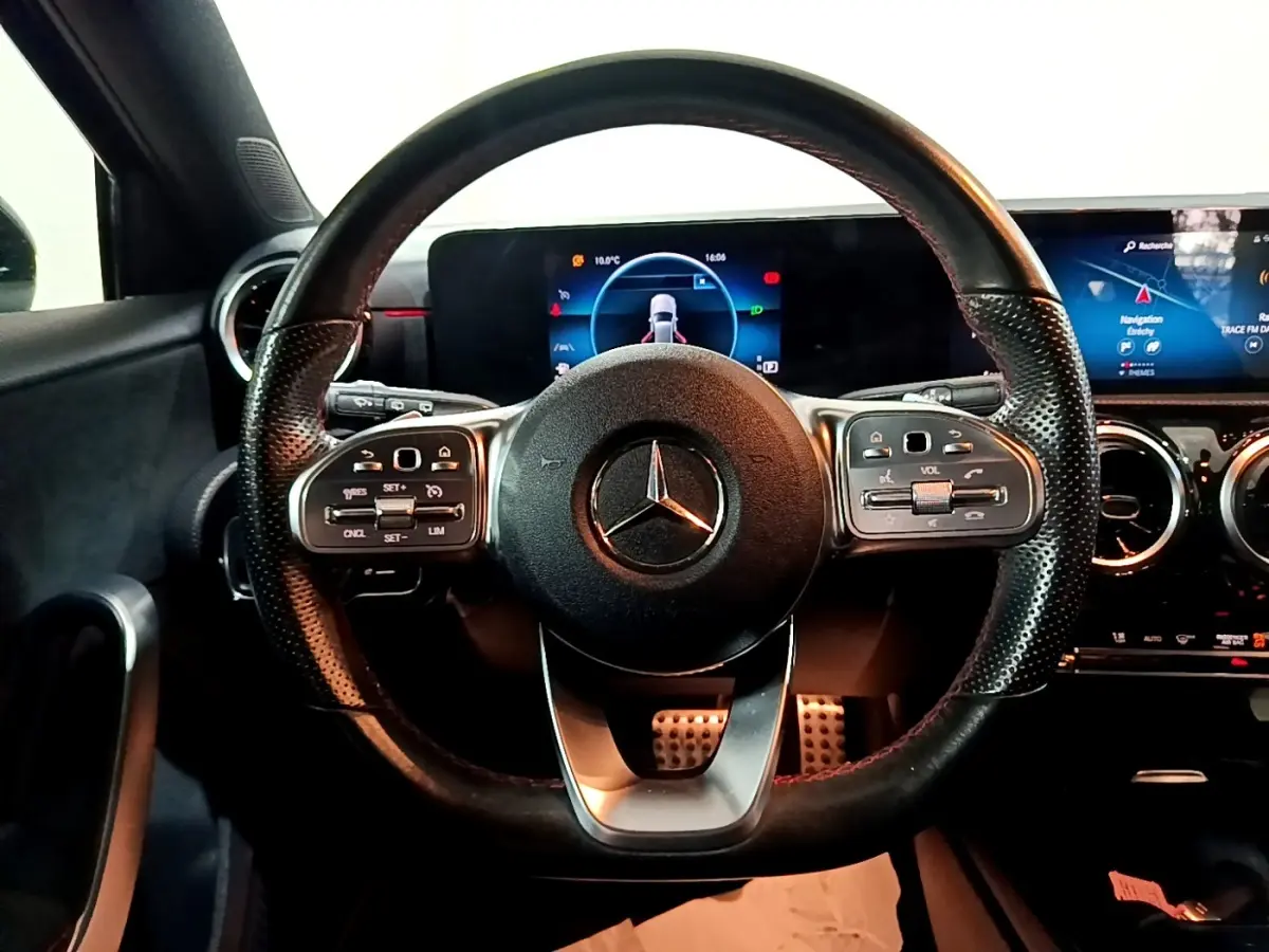 Vue intérieure centrée sur le volant cuir perforé noir de la Mercedes Classe A 200 AMG Line avec tableau de bord numérique.