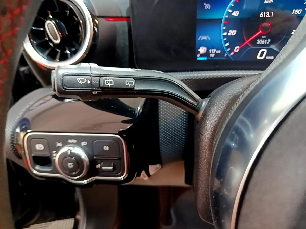 Gros plan sur la commande d’essuie-glace et le tableau de bord numérique bleu d’une Mercedes Classe A 200 AMG Line noire.