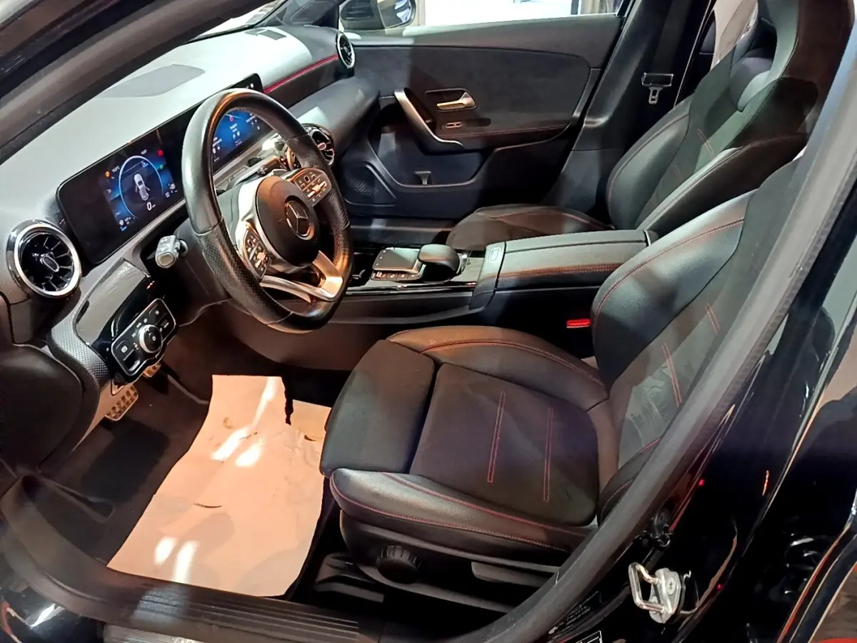 Vue intérieure côté conducteur de la Mercedes Classe A 200 AMG Line 2021 avec sièges noirs et tableau de bord digital.