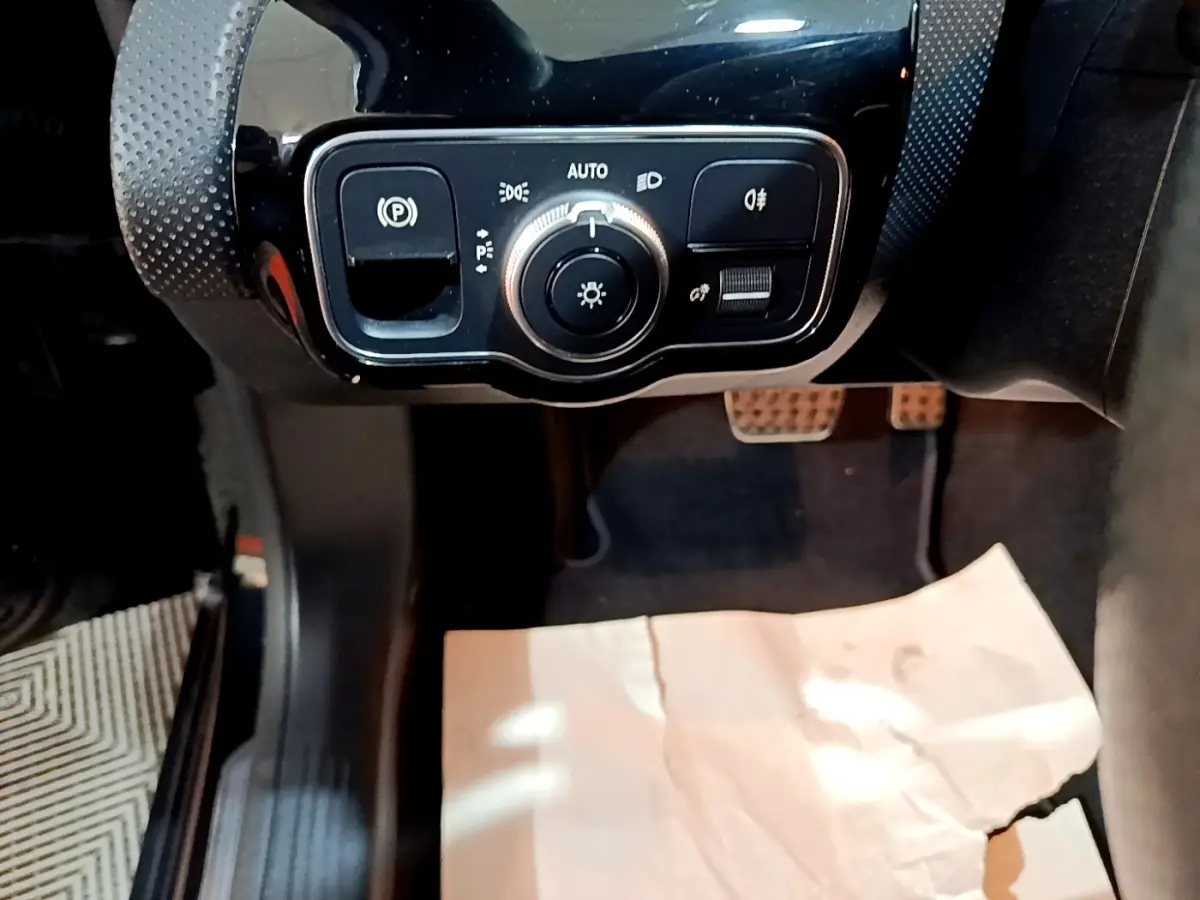 Gros plan sur les commandes d’éclairage et frein à main électrique dans l’habitacle noir d’une Mercedes Classe A A 200 AMG Line.