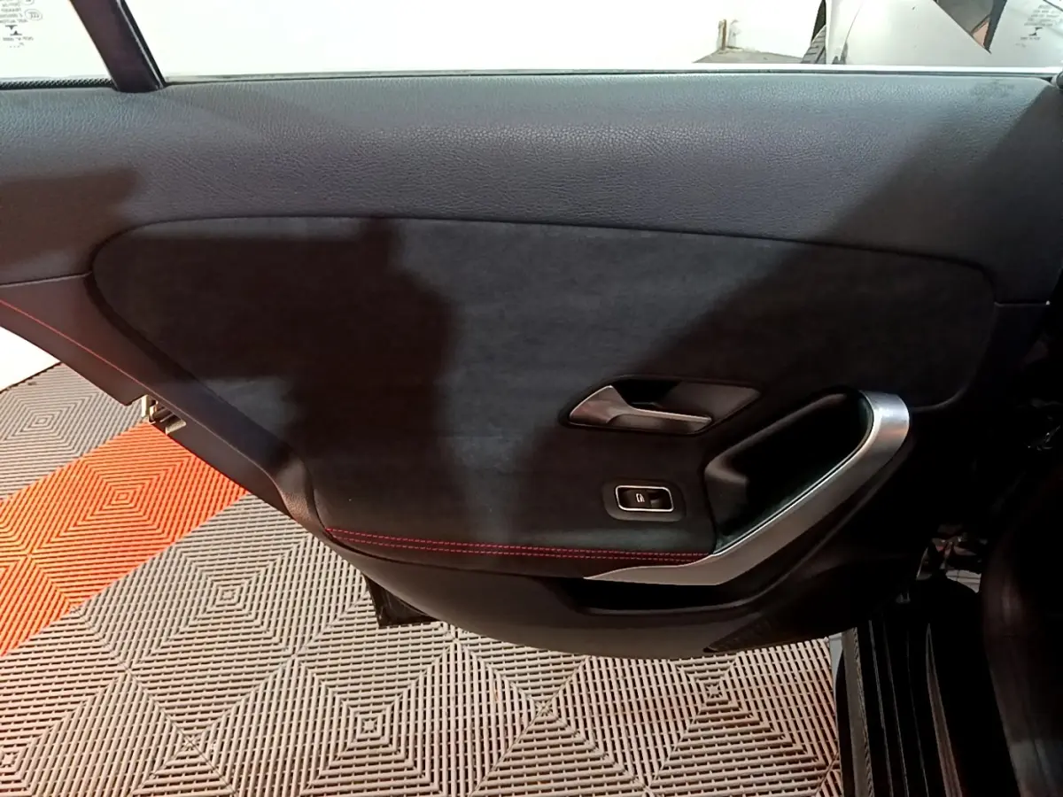 Vue intérieure du panneau de porte côté droit noir avec surpiqûres rouges et poignée argentée de la Mercedes Classe A 200 AMG Line.