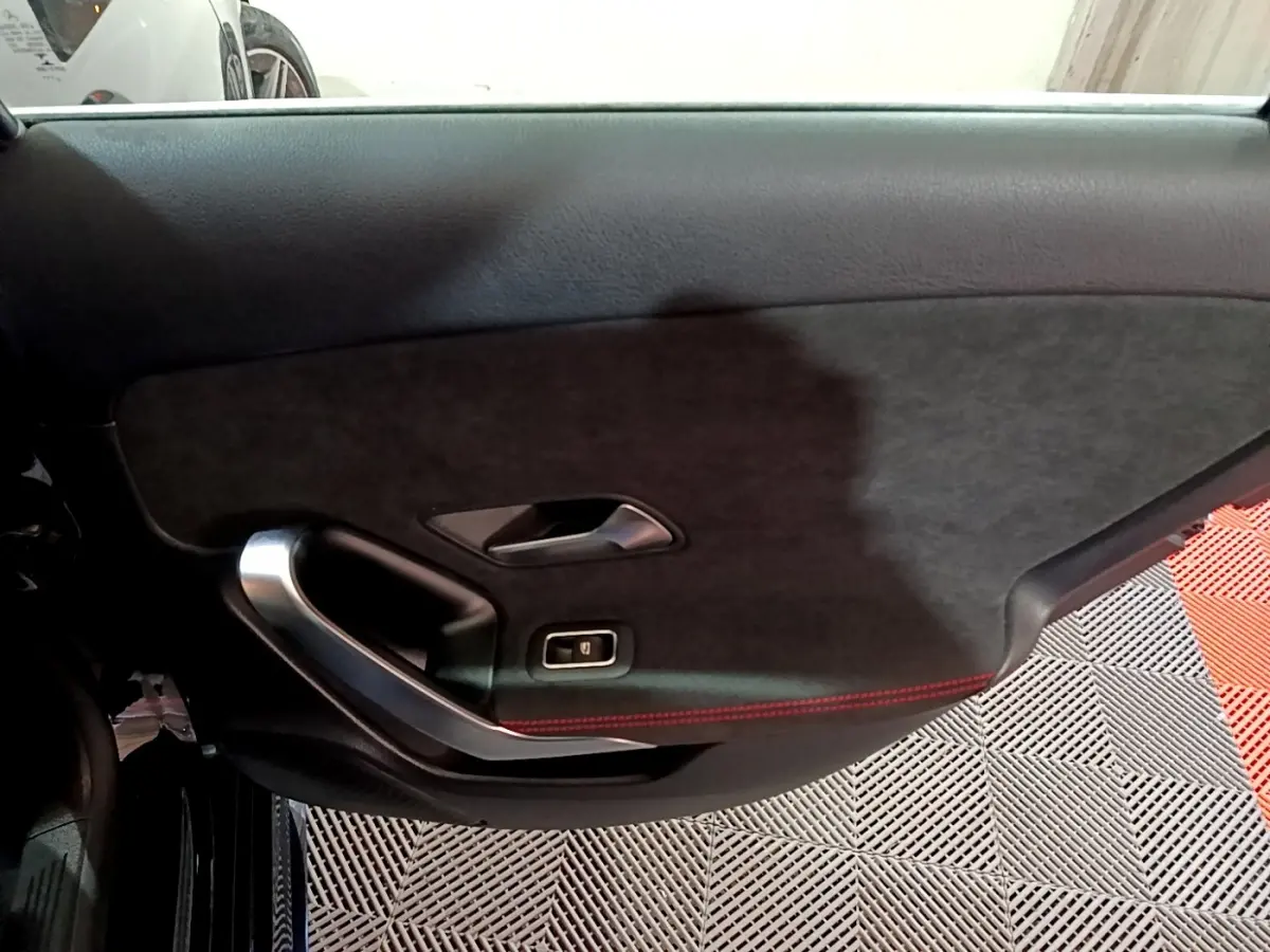 Gros plan sur la porte intérieure côté gauche noire avec surpiqûres rouges et poignée alu de la Mercedes Classe A AMG Line.