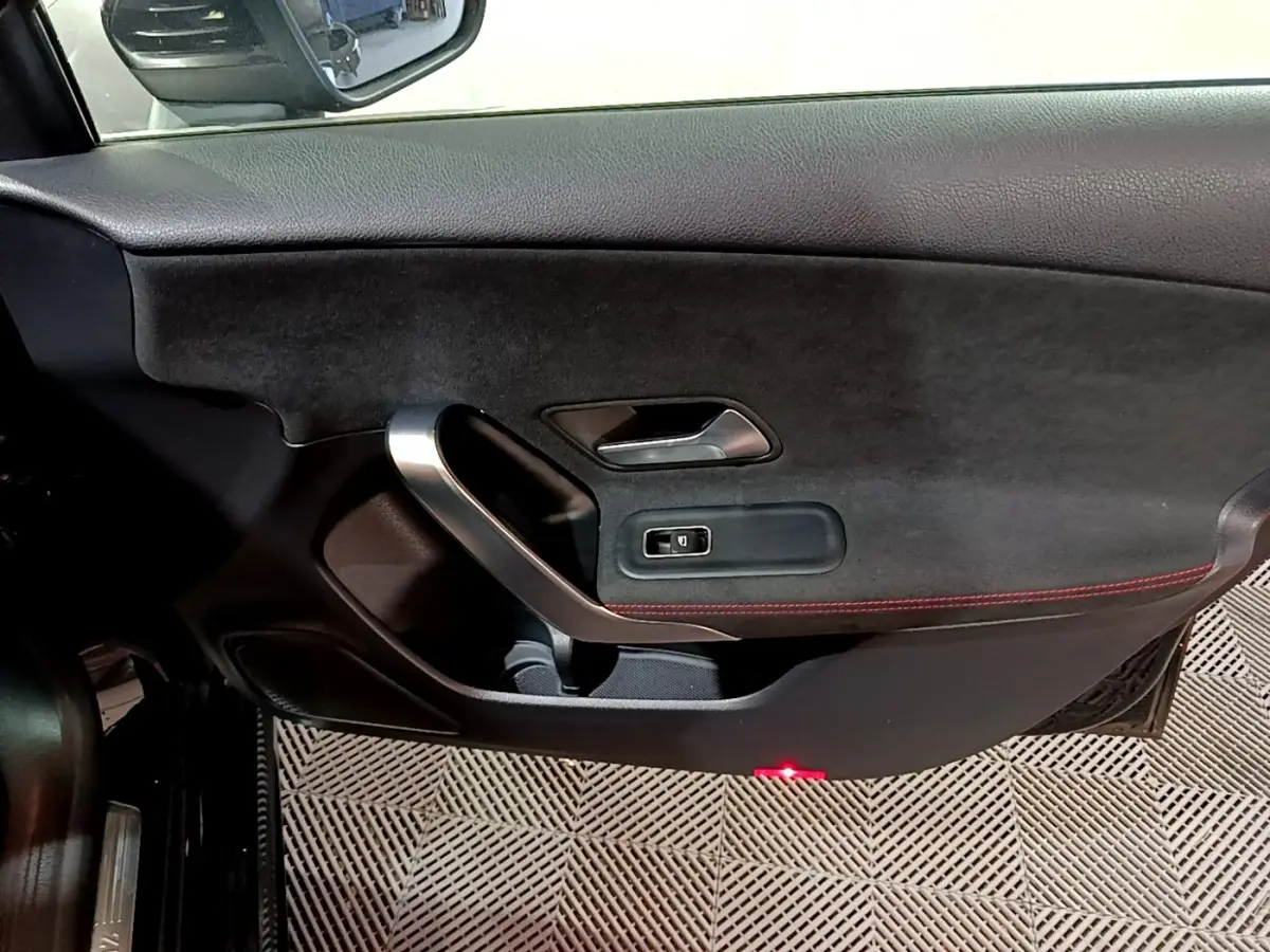 Vue intérieure du panneau de porte côté conducteur d'une Mercedes Classe A 200 AMG Line noir avec surpiqûres rouges.