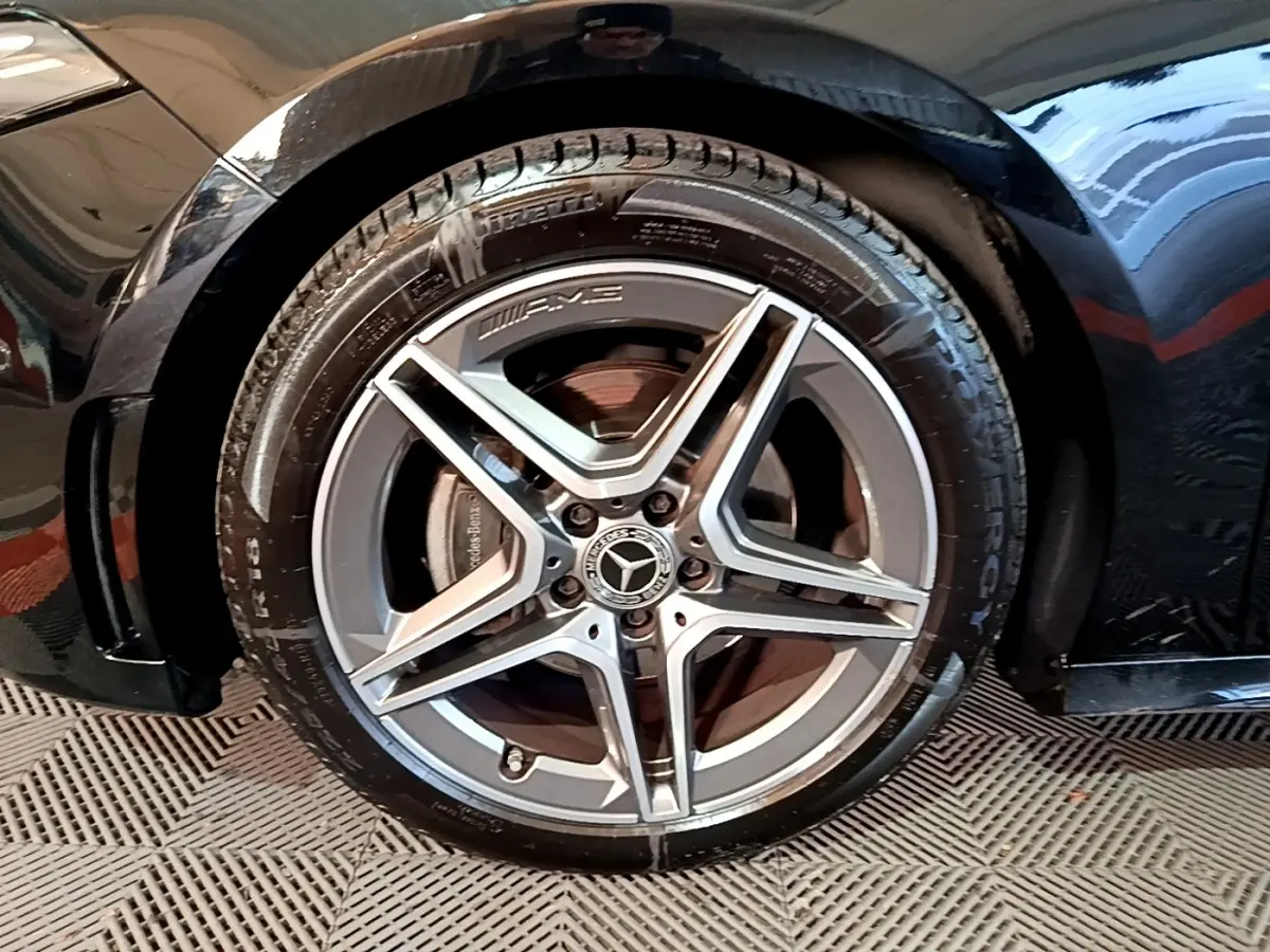 Gros plan sur la roue avant gauche noire d'une Mercedes Classe A 200 AMG Line avec jante AMG cinq branches.