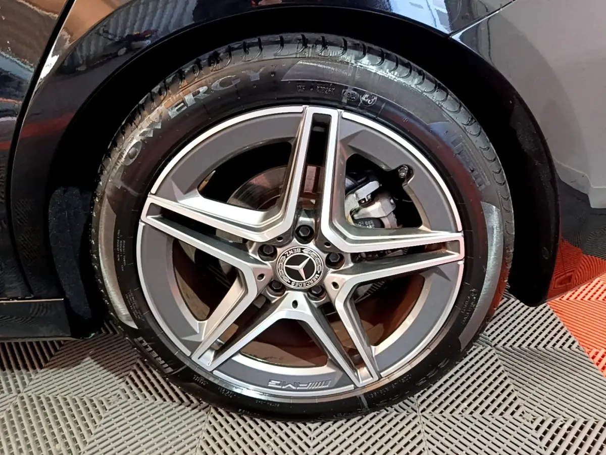 Gros plan sur la roue avant droite noire d'une Mercedes Classe A 200 AMG Line avec jante alliage AMG cinq branches.