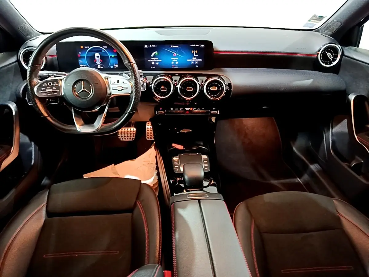 Vue intérieure avant de la Mercedes Classe A A 200 AMG Line 2021, tableau de bord noir avec éclairage rouge et écran tactile large.