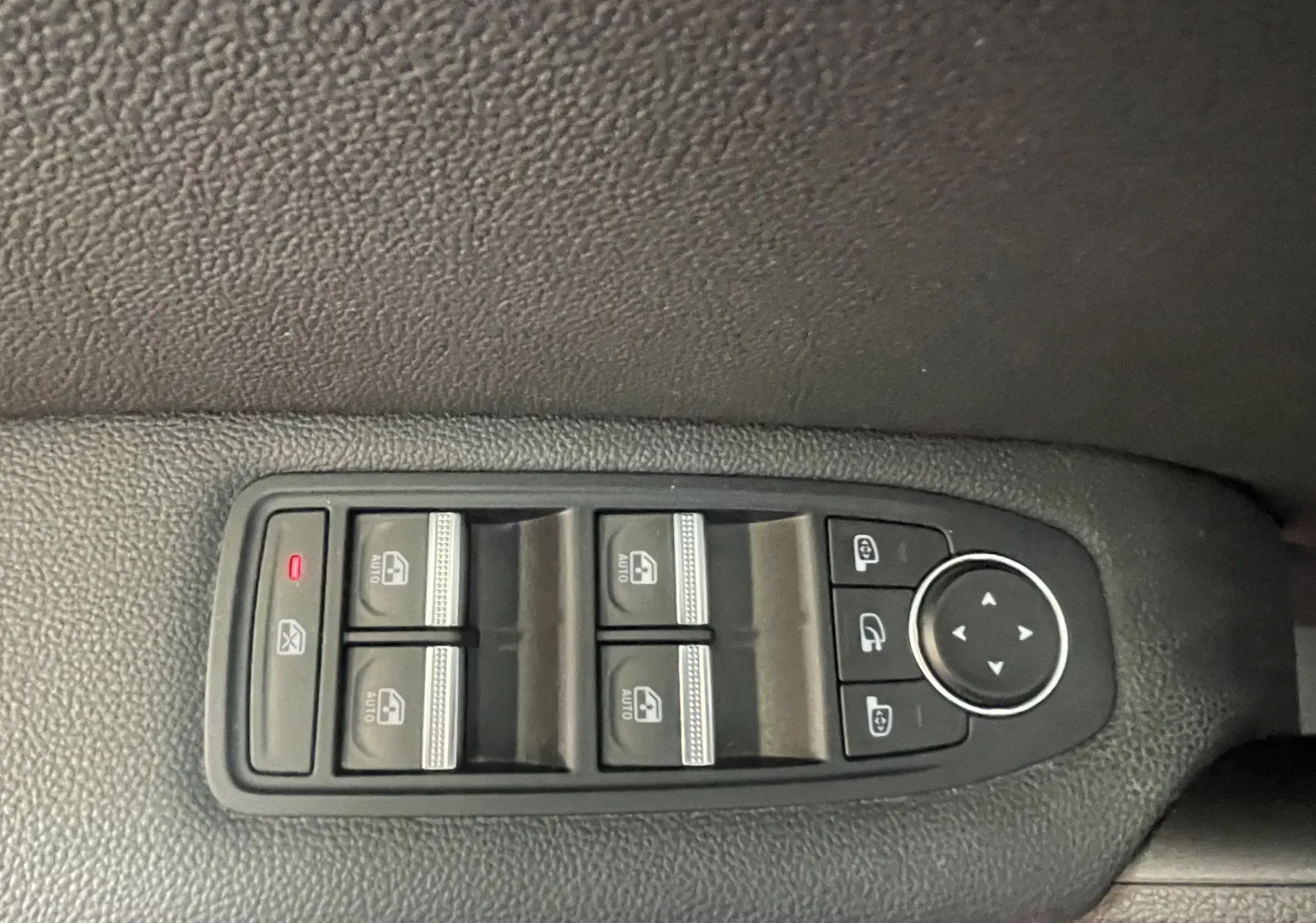 Panneau de commandes des vitres électriques et rétroviseurs sur porte intérieure noire d’un Renault Captur rouge, vue de dessus.