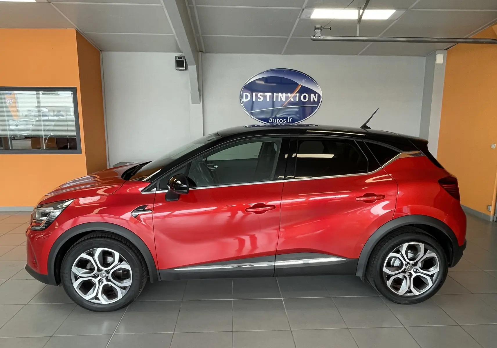 Profil droit d’un Renault Captur rouge 2019 avec toit noir, jantes alliage et protections noires sur les passages de roues.