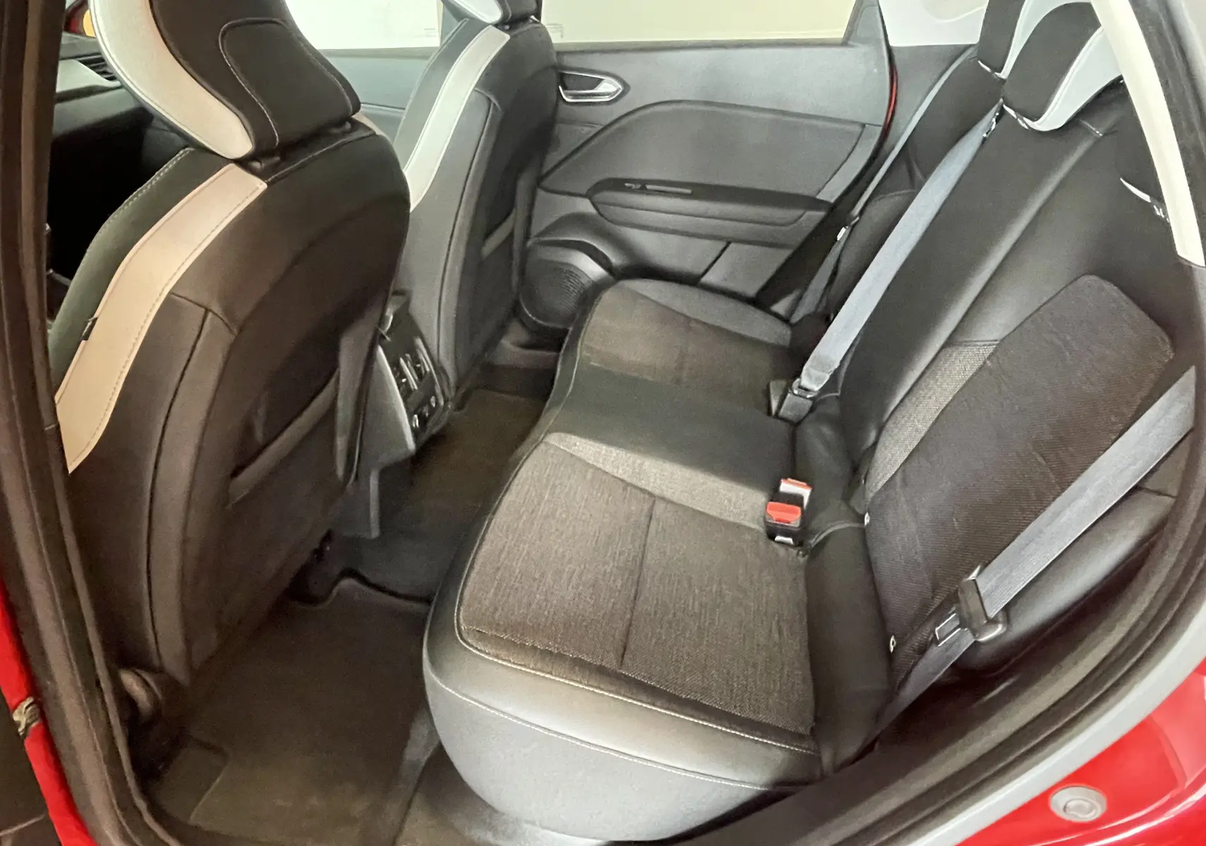 Vue intérieure arrière côté droit du Renault Captur rouge 2019, sièges arrière en tissu noir avec ceintures grises.