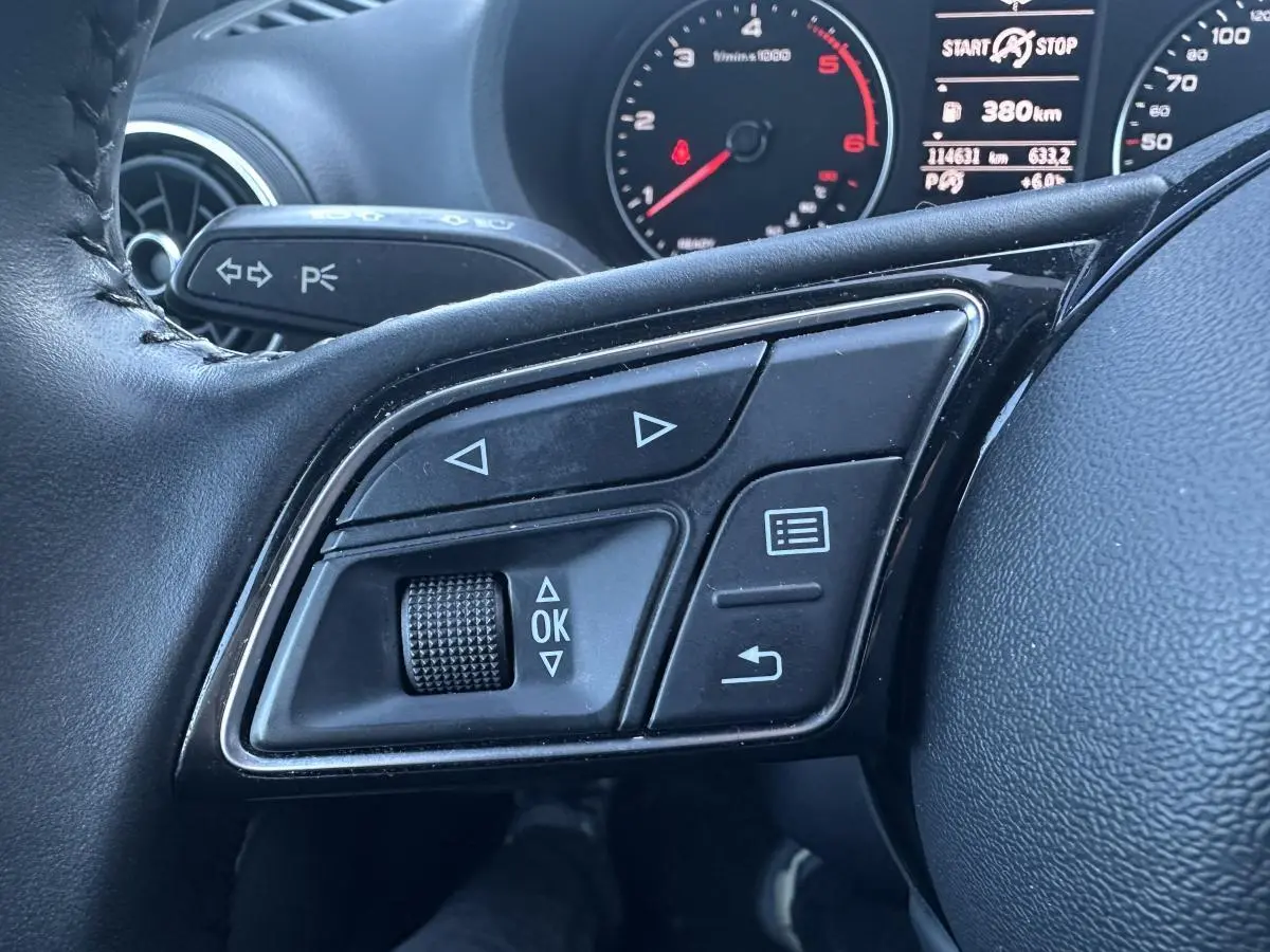 Gros plan sur les commandes multifonctions à gauche du volant cuir noir de l'Audi A3 berline 2020.
