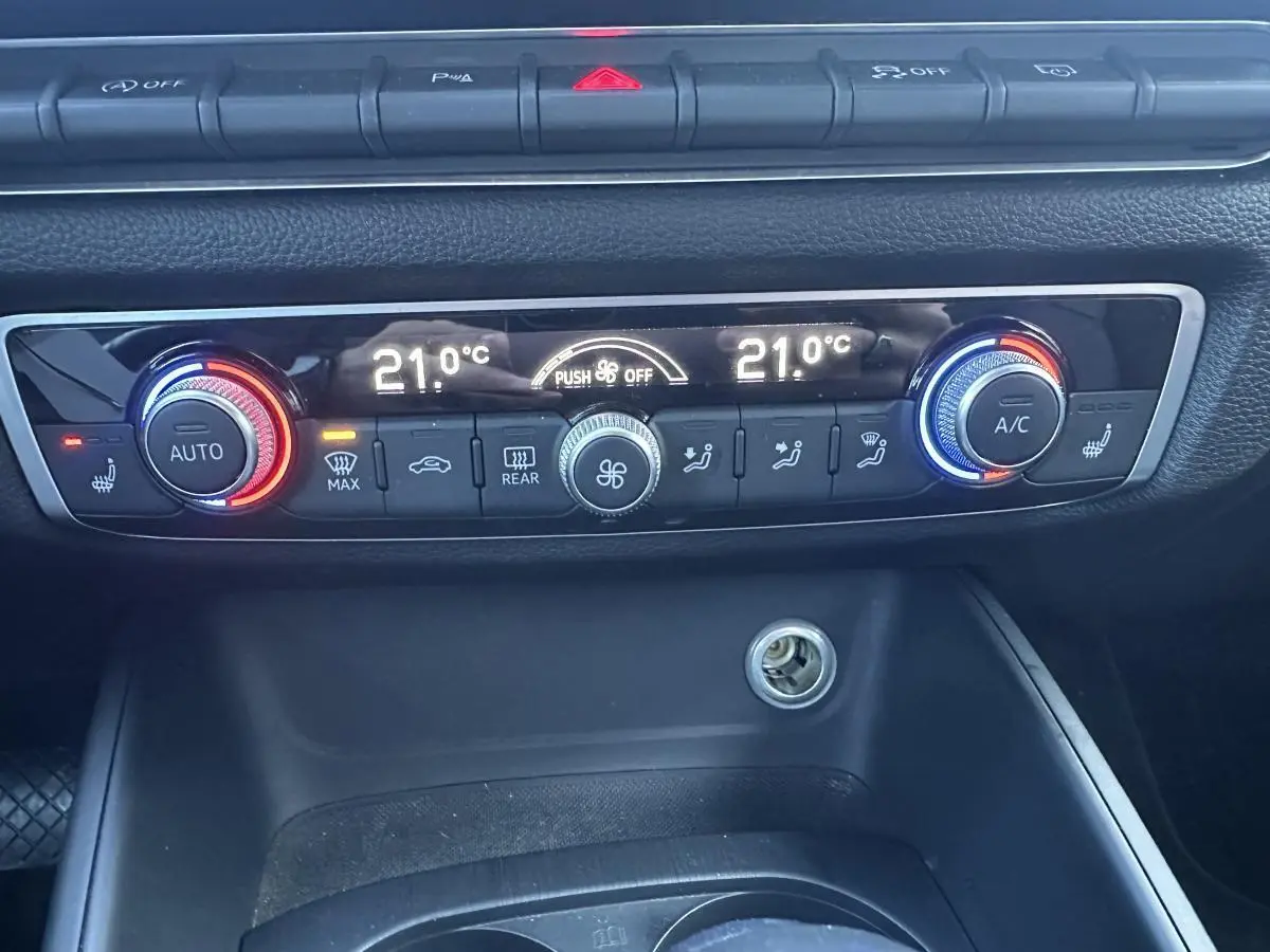 Vue rapprochée du tableau de bord de l'Audi A3 2020, montrant la climatisation automatique bi-zone avec réglages à 21°C.