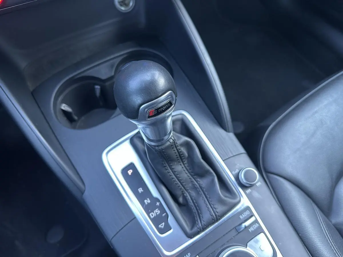 Le levier de vitesses automatique S tronic de l'Audi A3 noir, vu en gros plan depuis l'intérieur côté conducteur.