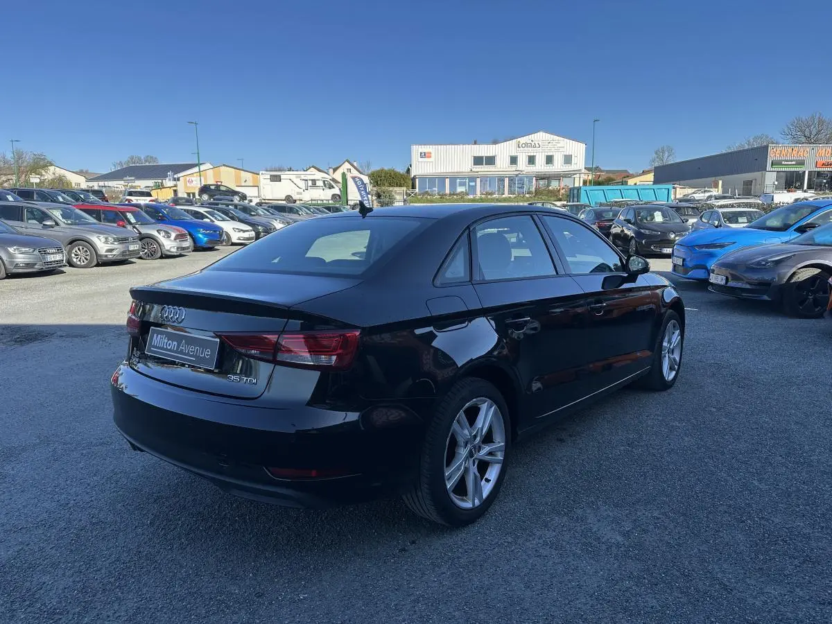 Audi A3 berline noire vue en 3/4 arrière droit sur un parking avec jantes aluminium 10 branches.