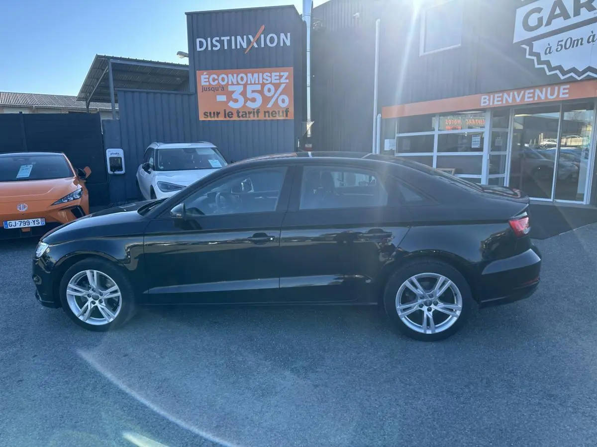 Audi A3 berline noire vue de profil côté gauche, avec jantes aluminium 10 branches et arrière compact.