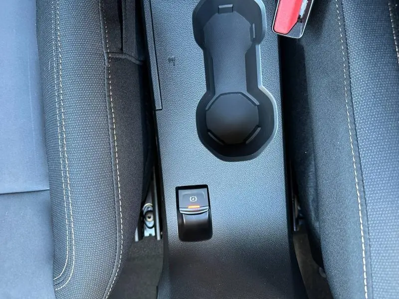 Gros plan sur la console centrale noire avec porte-gobelets et frein à main électrique du Dacia Jogger 2024.