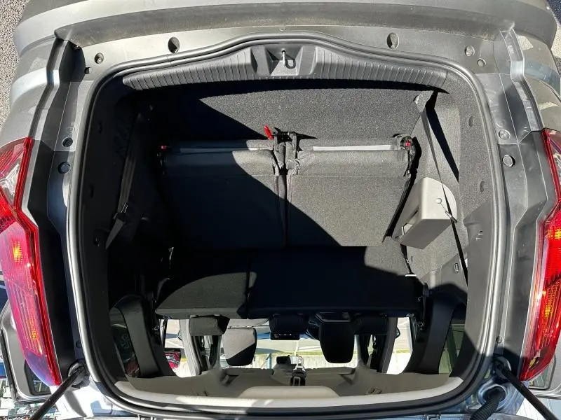 Vue plongeante sur le coffre ouvert d'un Dacia Jogger noir nacré, montrant la banquette arrière rabattue et les feux arrière allumés.