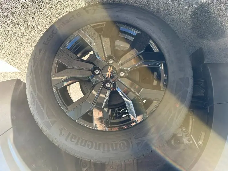 Gros plan sur la roue noire brillante avec jante alu au design moderne du Dacia Jogger 2024 Noir Nacré métallisé.