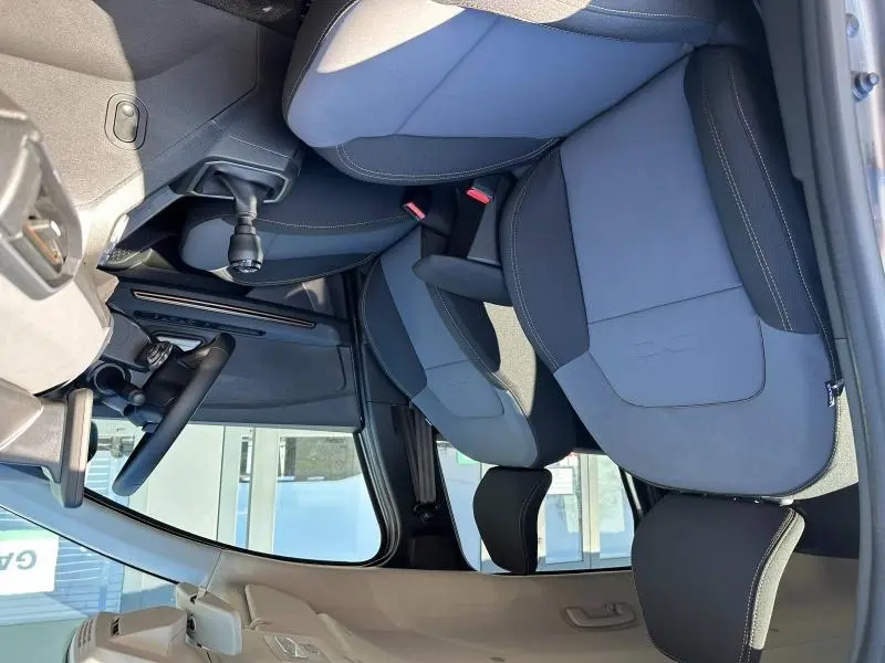 Vue intérieure côté conducteur du DACIA JOGGER 2024, sièges noirs avec surpiqûres blanches et levier de vitesse manuel visible.