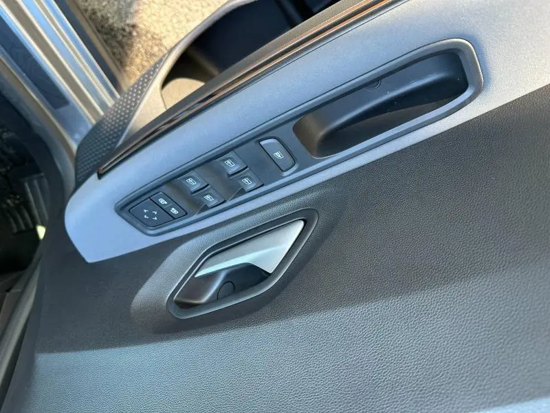 Détail de la porte avant gauche du Dacia Jogger 2024 avec commandes des vitres et poignée intérieure grise.