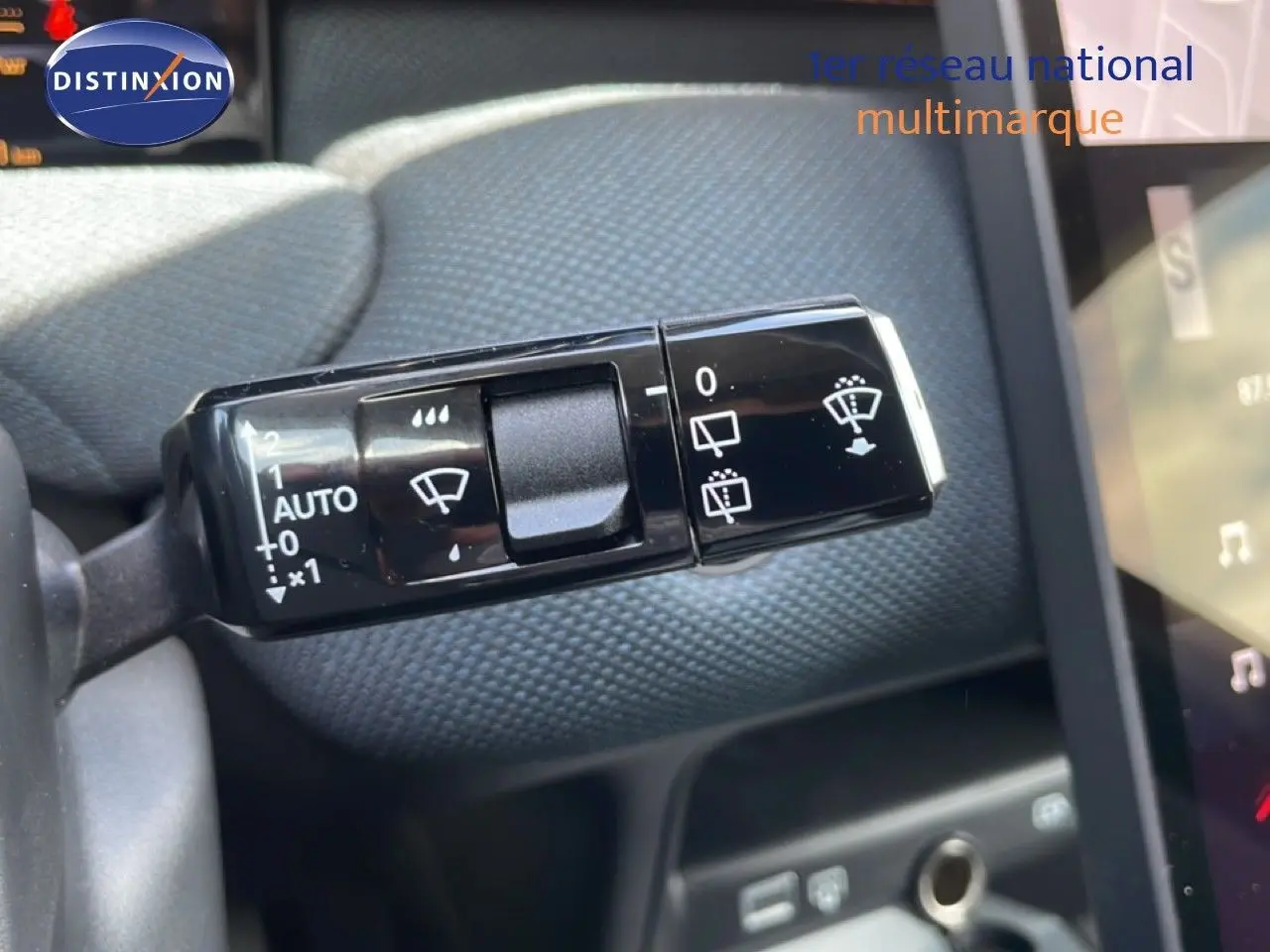 Gros plan sur la commande d’essuie-glace du Citroën C5 Aircross Hybrid, avec tableau de bord et tissu gris en arrière-plan.
