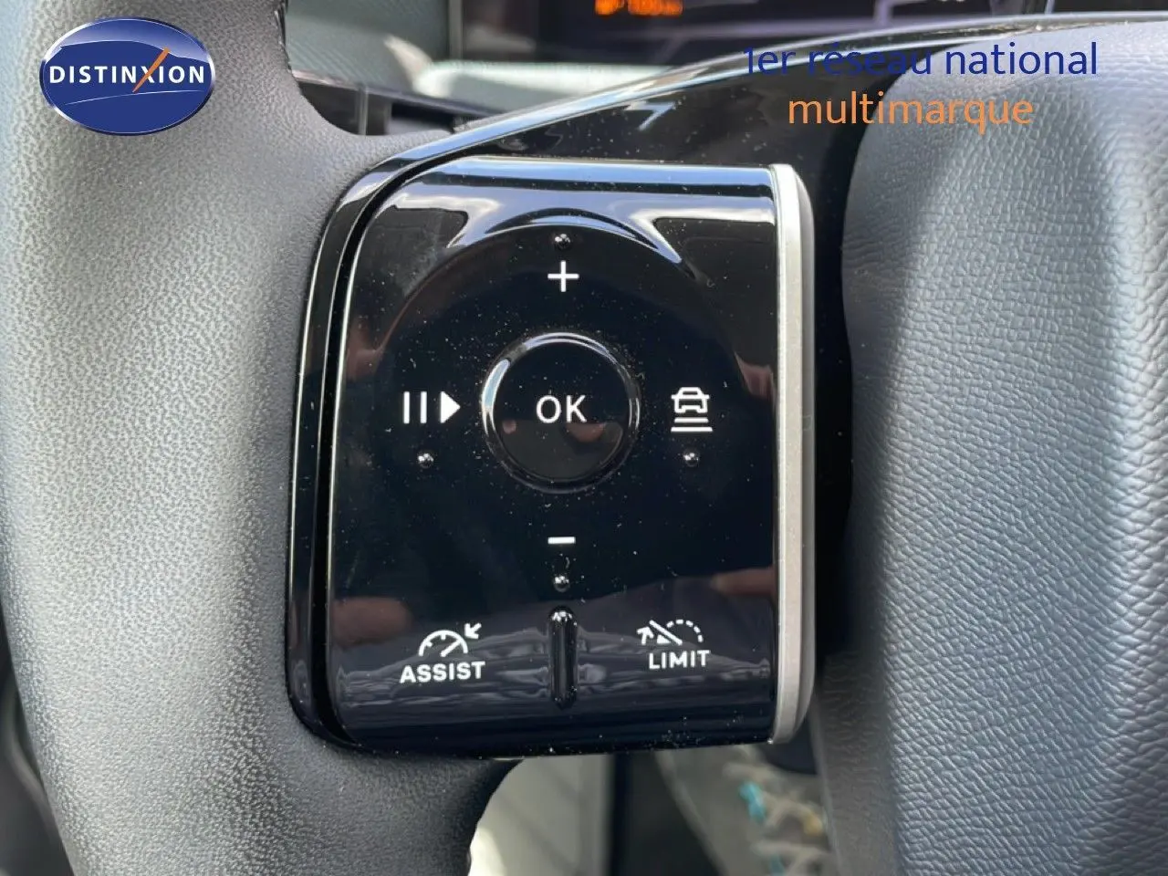 Gros plan sur les commandes noires du volant du Citroën C5 Aircross Hybrid rouge rubis, avec boutons d'assistance et limitation.