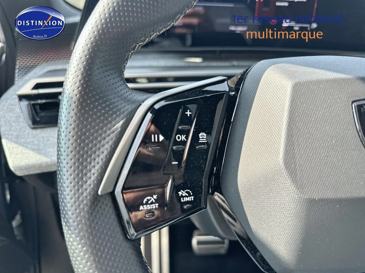 Gros plan sur le volant cuir perforé côté gauche du Peugeot 3008 gris Artense, avec commandes multifonctions visibles.