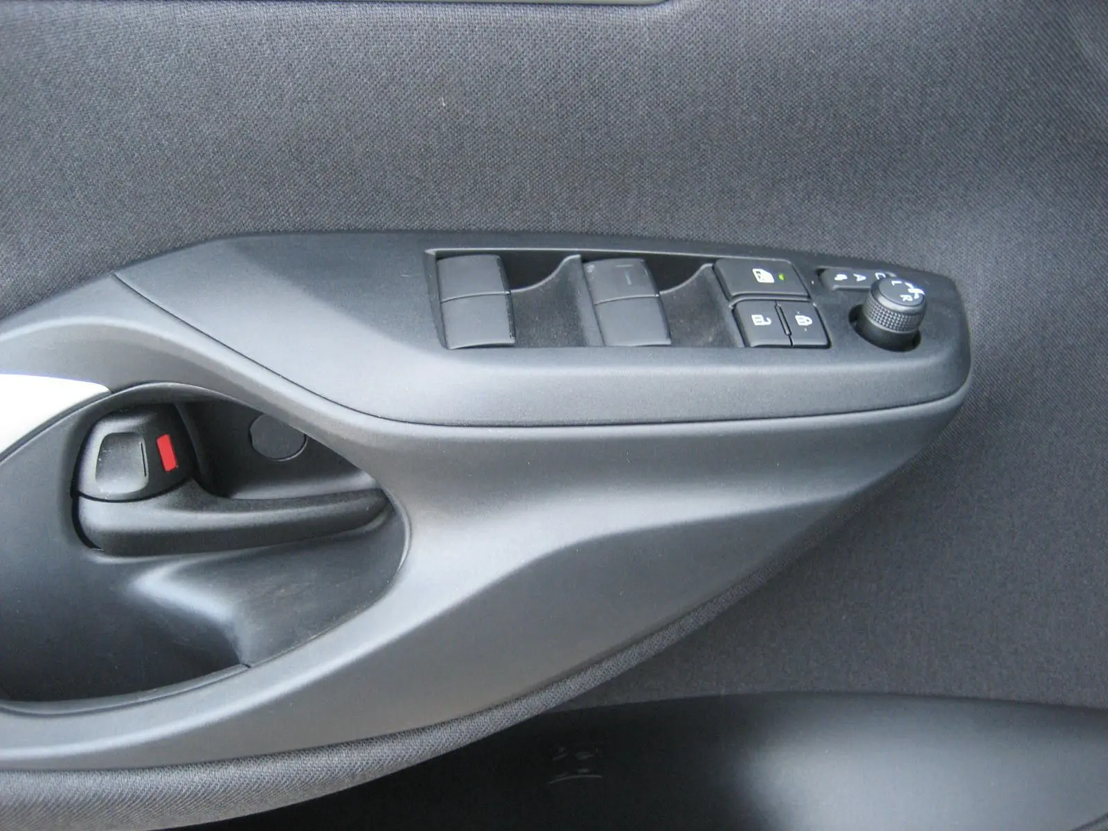Gros plan sur la commande de porte côté gauche de la Toyota Yaris Cross 2025, avec boutons de réglage des vitres et rétroviseurs.