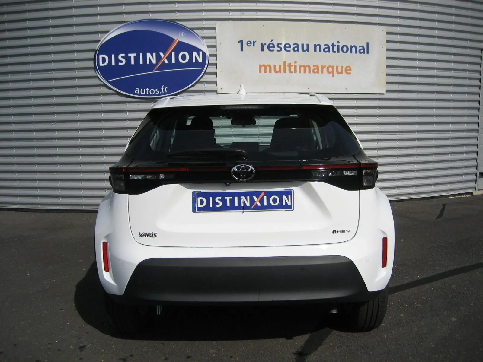 Vue arrière d'une Toyota Yaris Cross blanche 2025 avec feux arrière noirs et logo hybride visible.