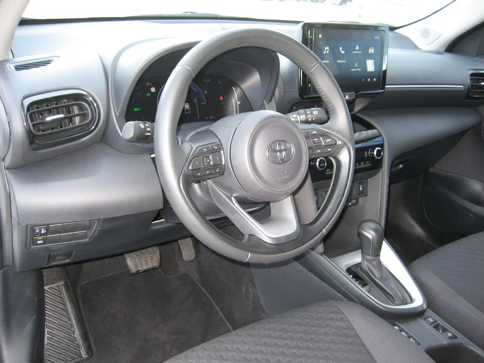 Vue intérieure de la Toyota Yaris Cross 2025, tableau de bord et volant multifonction en noir, avec écran tactile central.