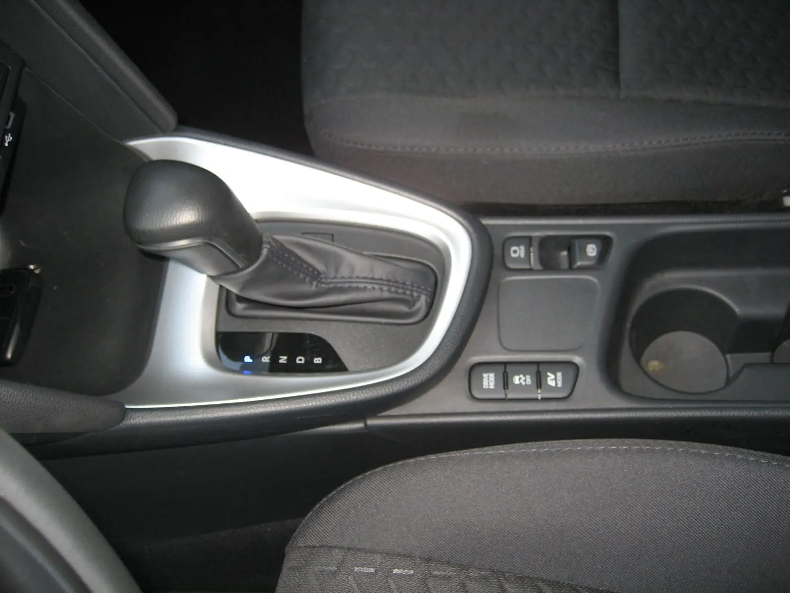 Gros plan sur la console centrale intérieure de la Toyota Yaris Cross 2025, avec levier de vitesse automatique et commandes hybrides.