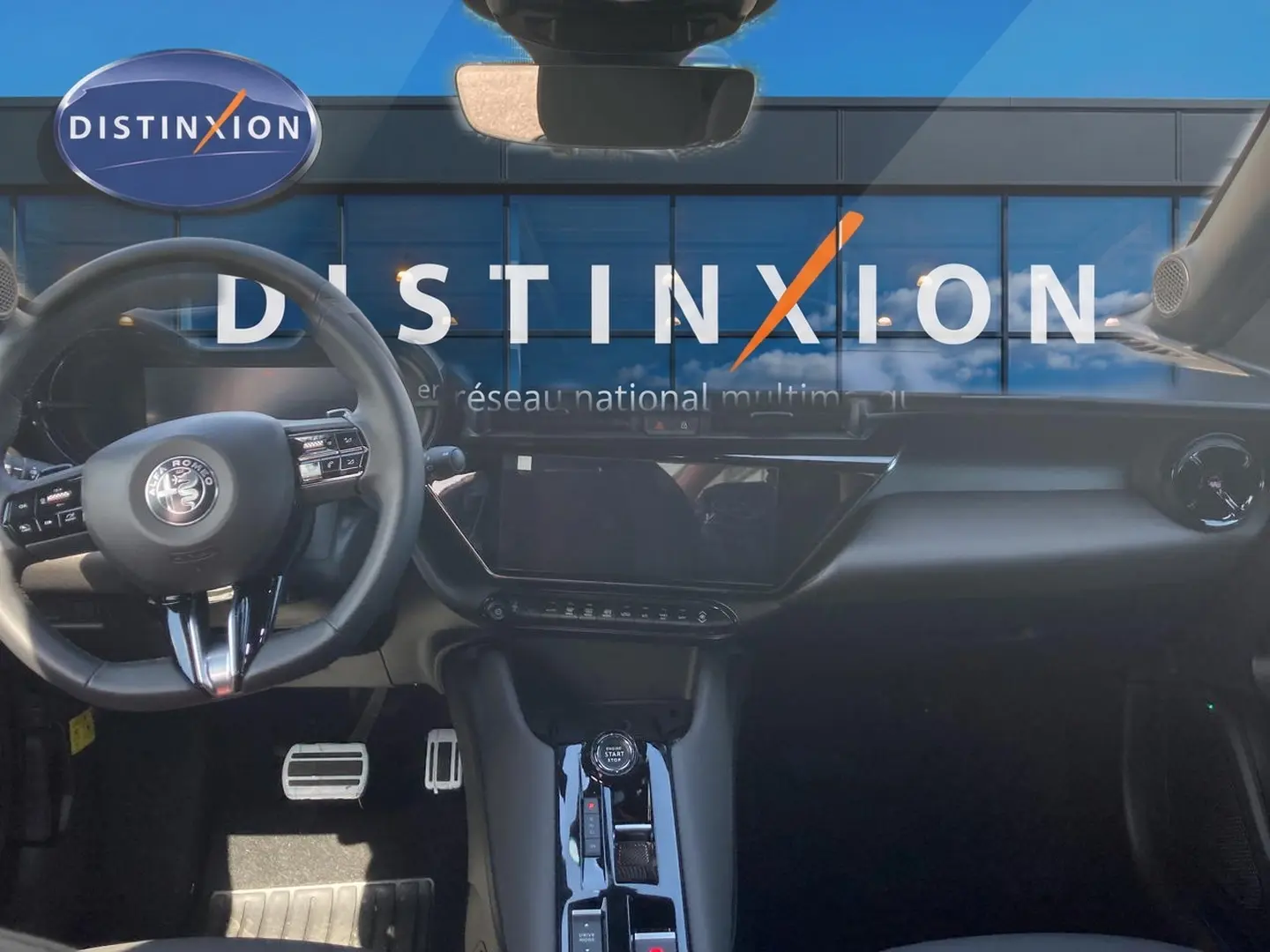 Intérieur de l'Alfa Romeo Junior 1.2 hybride 2026, vue frontale du tableau de bord noir avec écran tactile et volant multifonction.