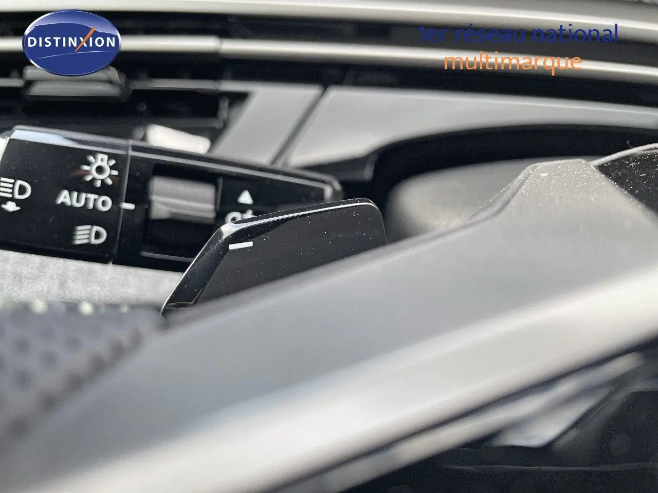 Gros plan sur la commande des phares automatiques et la palette de changement de vitesse du Peugeot 5008 noir perle métal.