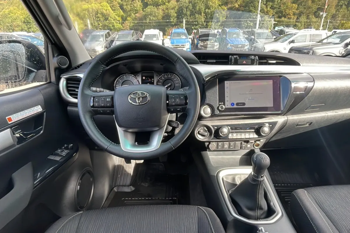 Intérieur du Toyota Hilux 2025 en vue frontale, montrant le volant, tableau de bord et levier de vitesse manuel.
