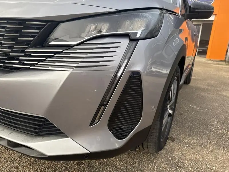 Gros plan sur l'avant droit gris Artense du Peugeot 3008 2022, mettant en valeur le phare LED et la calandre chromée.