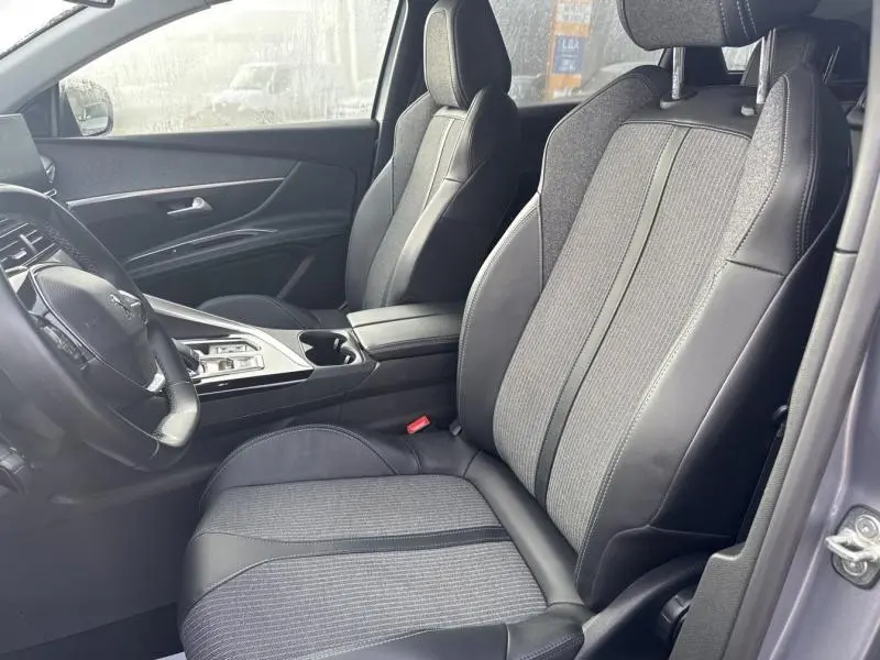 Vue intérieure côté conducteur du Peugeot 3008 2022 avec sièges en tissu gris et cuir noir, console centrale moderne.