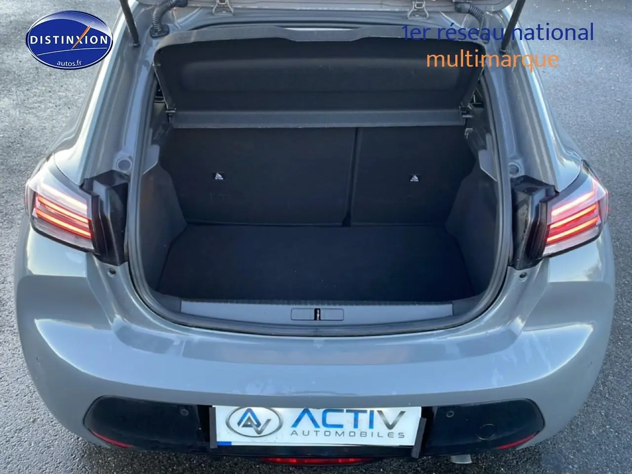 Vue arrière ouverte du coffre d'une Peugeot 208 1.2 100 Allure gris sélénite avec feux arrière allumés.