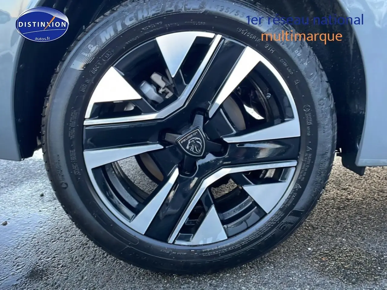 Gros plan sur la jante alu noire et argentée d'une Peugeot 208 gris sélénite, vue côté droit avant.