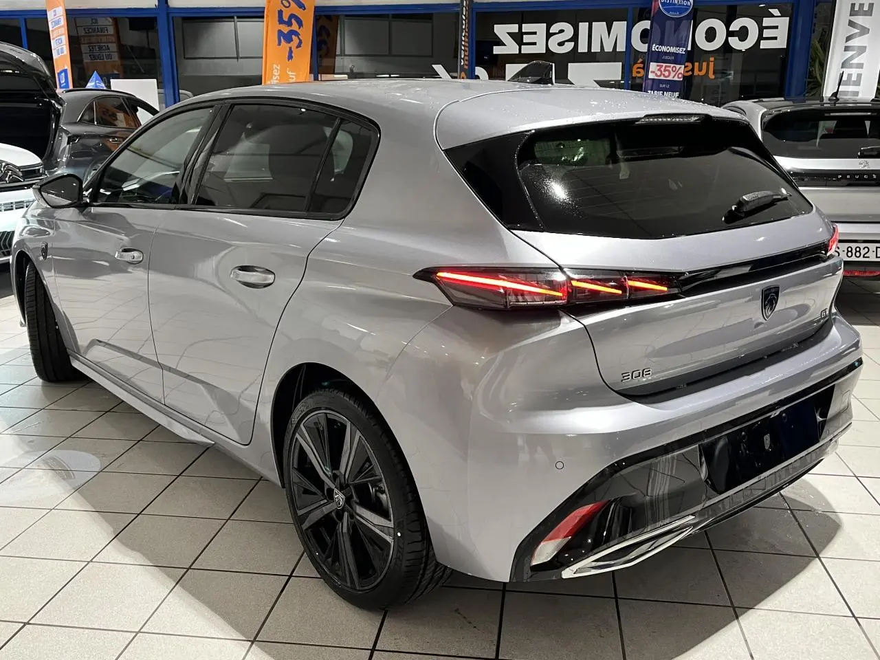Vue 3/4 arrière droite de la Peugeot 308 2024 gris Artense avec feux arrière LED et jantes alliage 18 pouces noires.