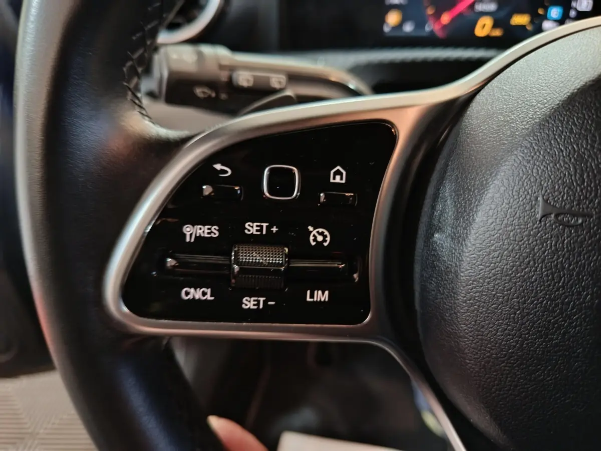 Gros plan sur le côté gauche du volant cuir de la Mercedes Classe A 250 e Business Line 2021 avec commandes intégrées.