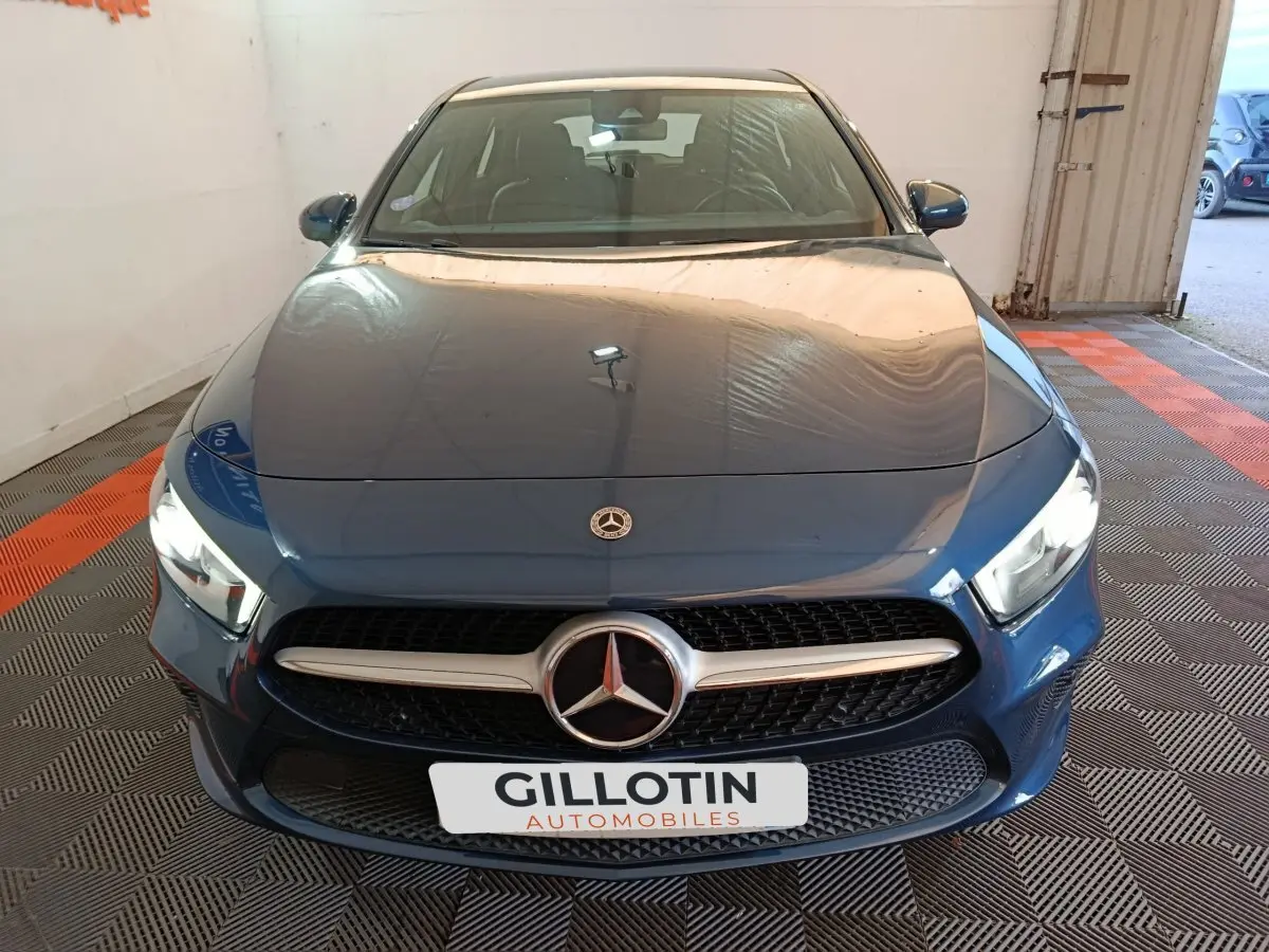 Vue avant d'une Mercedes Classe A bleu avec calandre chromée et phares allumés dans un garage.