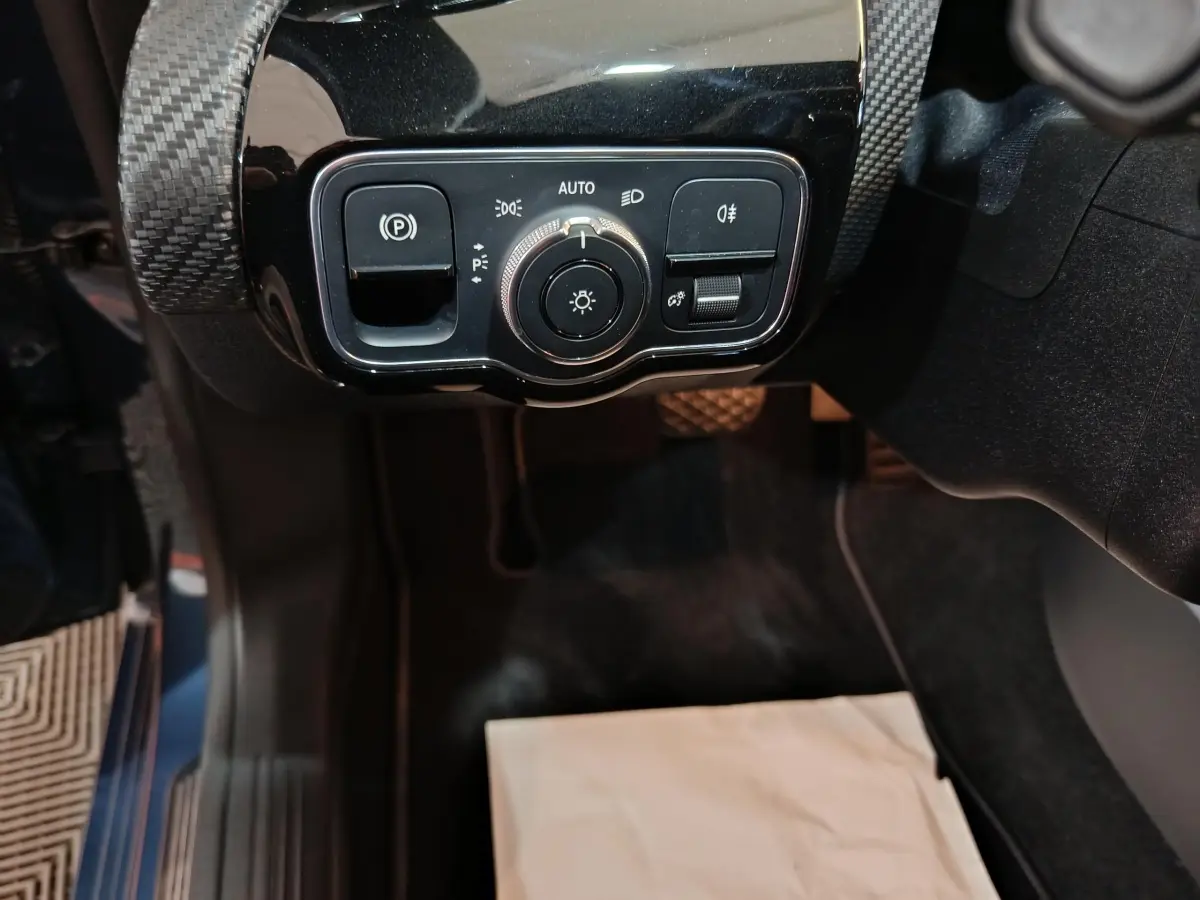 Gros plan sur les commandes d'éclairage et frein à main électrique dans une Mercedes Classe A 250 e Business Line bleu.