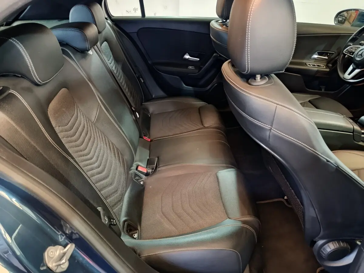 Vue intérieure côté arrière droit de la Mercedes Classe A 250 e Business Line 2021 avec sièges en cuir noirs et détails tissu.