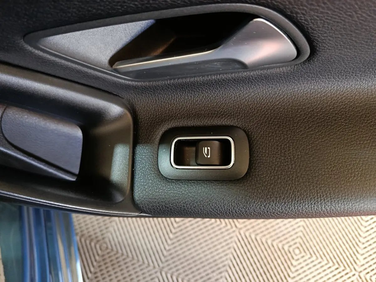 Bouton de commande de vitre électrique sur la porte intérieure côté gauche d’une Mercedes Classe A bleu.