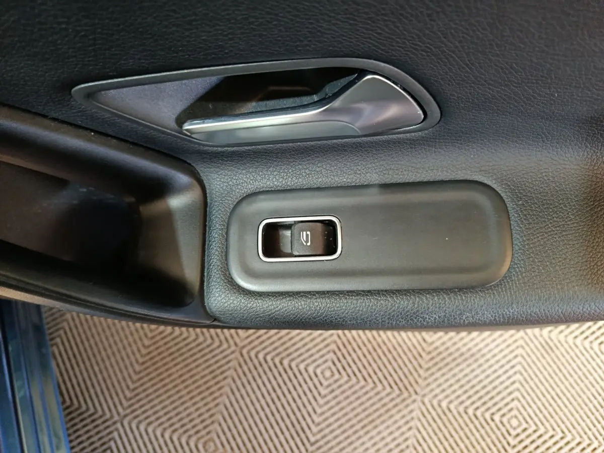 Gros plan sur la commande de lève-vitre côté conducteur d'une Mercedes Classe A 250 e Business Line bleu.